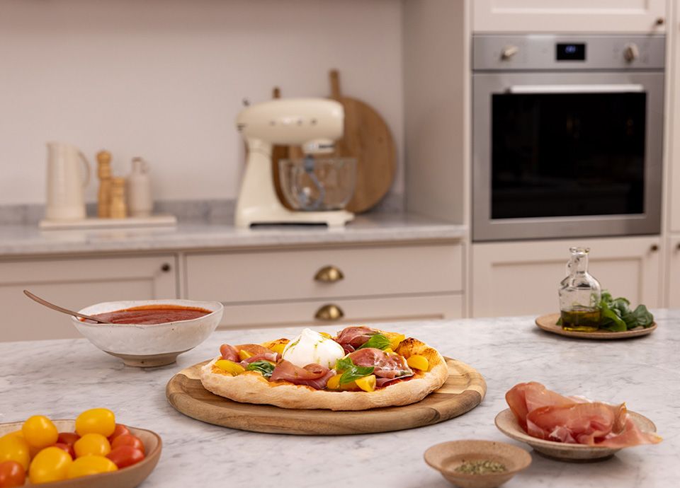 Pizza margherita con prosciutto crudo, pomodorini gialli, burrata e olio al basilico