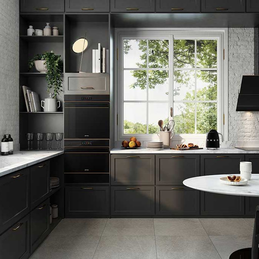 large kitch with dark units, white marble worktop and two of Smeg's built in ovens in column arrangement