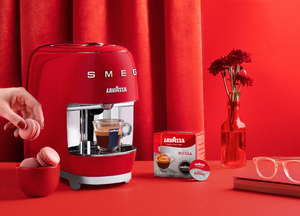 Lavazza A Modo Mio Smeg rossa con tazzina di caffè e dolcetti