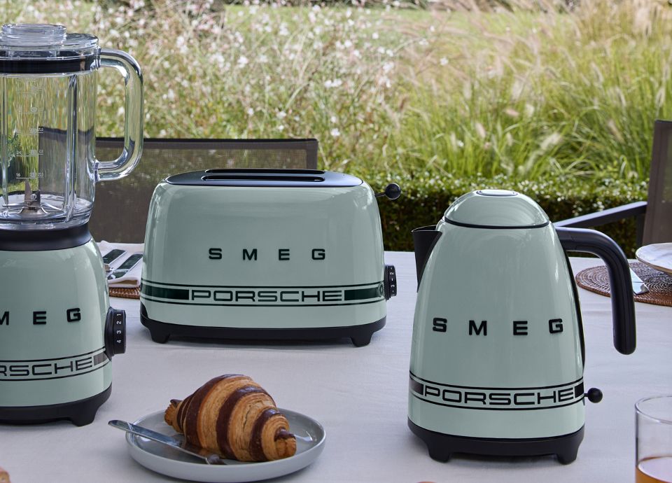 Encimera de cocina con tres electrodomésticos de la colección Porsche x SMEG Shade Green. Los tres electrodomésticos están dispuestos de forma frontal y con un fondo de vegetación verde.
