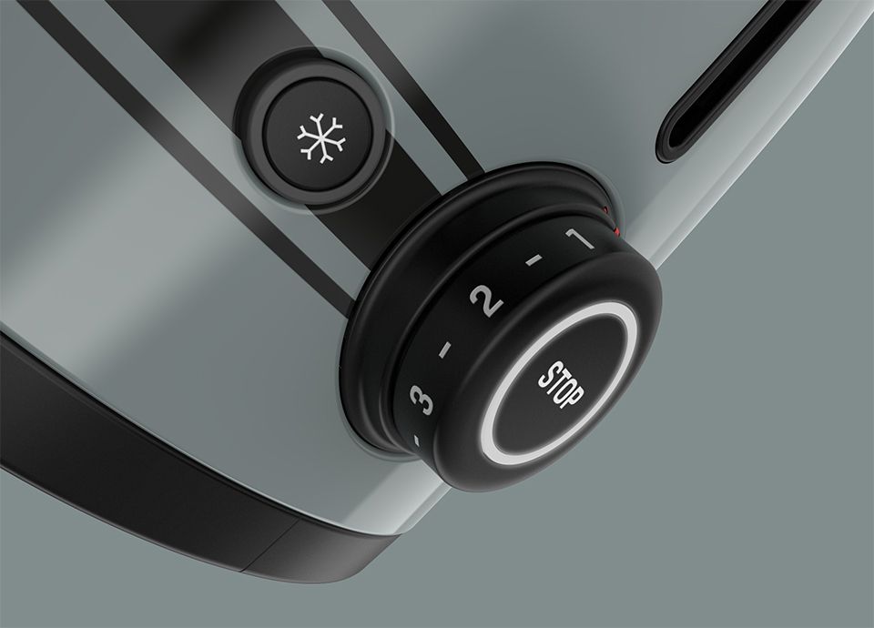 Detail of the control knob of the toaster in colour shade green. The black control knob is positioned on the right side of the base of the toaster and displays the different settings in white.