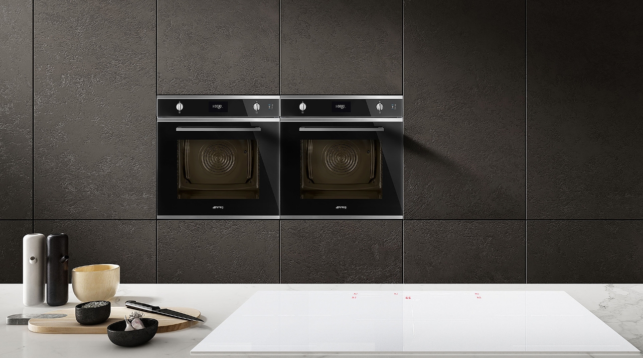 Cucina moderna con due forni da incasso neri, progettata per facilitare la cottura e la preparazione dei pasti.